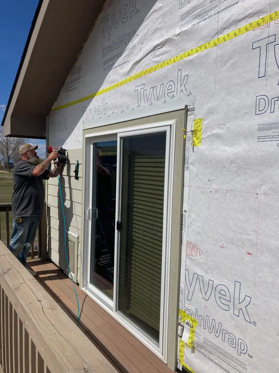 Crew member installing siding and weather barrier detail