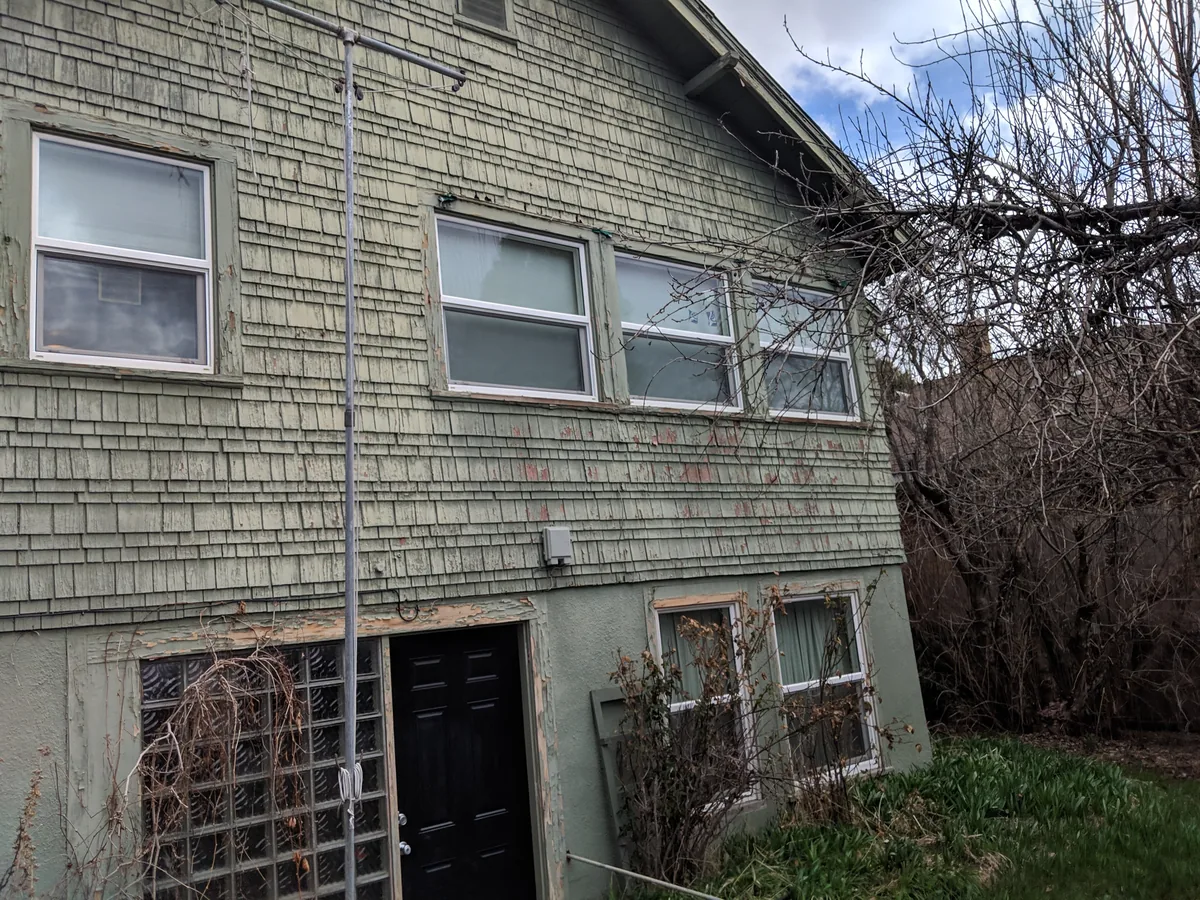 Before siding replacement showing worn shingle siding and weathered trim